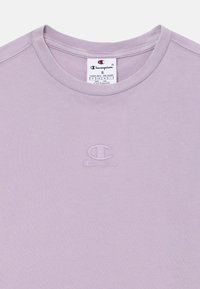 Lys lavendel t-skjorte laget av bomull med rund hals. Har en liten brodert Champion-logo på brystet.