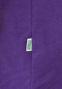 Lilla bomullsstoff med en teksturert finish, som har en hvit lapp merket "URBAN CLASSICS" sydd inn i sidesømmen.