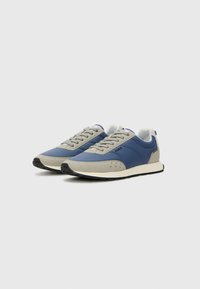 Sneakers i blå och grå material, med en slät textur, rund tå, snörningsdesign och en gummisula med friktionsdetaljer.