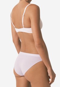 Witte beha met dunne bandjes, naadloos ontwerp en verstelbare sluiting aan de achterzijde; gecombineerd met bijpassende witte naadloze slipjes. Zachte katoentextuur.
