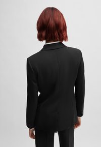 Svart blazer med skr�äddarsydd passform, med en notch-krage, enkel sprund bak och knappade manschetter. Slät tygstruktur.