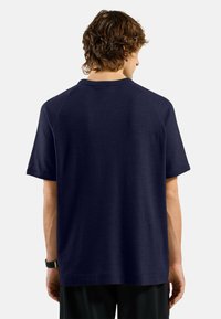 T-shirt a maniche corte di colore blu navy con un motivo a nido d'ape e maniche raglan. Presenta un colletto a girocollo e una vestibilità rilassata.