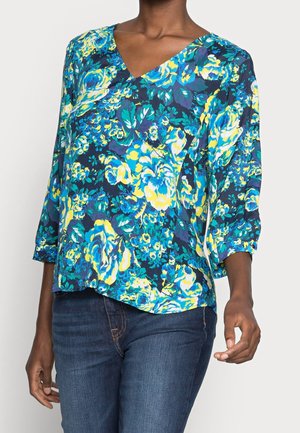 Blumenbluse in Marineblau mit lebendigen blauen, gelben und grünen Mustern. Verfügt über einen V-Ausschnitt und Dreiviertelärmel mit lockerer Passform.