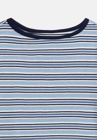 Κοντινή λήψη υφάσματος με οριζόντιες ρίγες σε μπλε, λευκό κ αι μαύρο, με λαιμόκοψη σε σκούρο μπλε χρώμα.