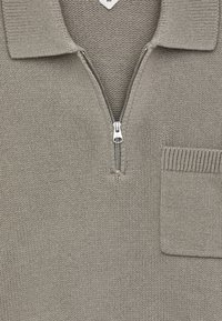 Helle graue Strickpullover mit einem Halbzip-Kragen, ausgestattet mit einer aufgesetzten Tasche auf der Brust und strukturiertem Stoff.