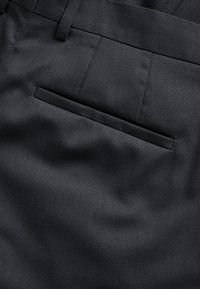 Černé kalhoty na míru se šikmým žebrováním, rovného střihu a jednou paspuli na zadní straně.