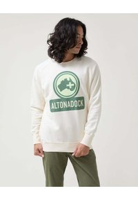 Sudadera color crema de algodón, con un gran gráfico verde de Australia con una cruz y el texto "ALTONADOCK". Puños ajustados.