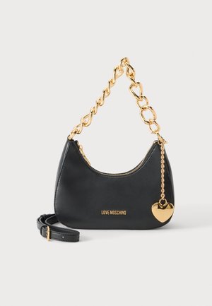 Sac à main Moschino noir avec une anse chaîne dorée épaisse, une bandoulière et un pendentif cœur doré sur fond blanc.