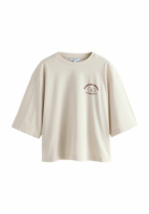 Béžové oversized bavlnené tričko s krátkymi rukávmi, na prednej strane so potlačou loga v tmavohnedej farbe. Okrúhly výstrih, voľný strih.