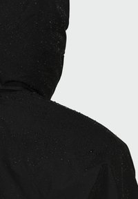 Czarna wodoodporna kurtka z kapturem, o gładkiej fakturze i widocznymi kroplami wody na powierzchni, podkreślająca jej wodoodporność.