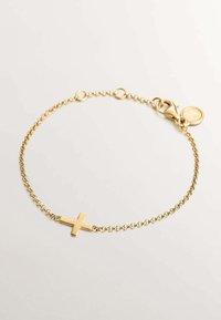 Pulsera de cadena de oro con un colgante de cruz pulido, con un cierre de langosta y una pequeña etiqueta de logo, que muestra un diseño delicado y una textura suave.