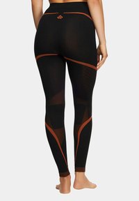 Czarne legginsy z pomarańczowymi akcentami i teksturowanymi panelami, z wysokim stanem i dopasowanym krojem, który podkreśla nogi.
