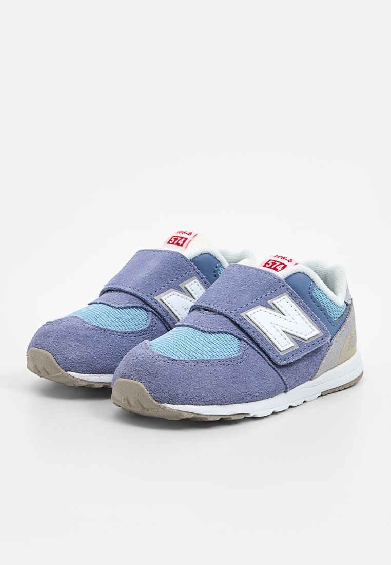 Blaue und graue New Balance Sneakers aus Wildleder und Mesh-Material, ausgestattet mit einem Klettverschluss, einem weißen "N"-Logo und einer strukturierten Gummisohle.