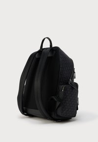 Μαύρο σακίδιο πλάτης με επενδυμένους ρυθμιζόμενους ιμάντες και μπροστινή τσέπη με φερμουάρ, με επαναλαμβανόμενο μοτίβο λογοτύπου MK σε σκούρο ύφασμα.