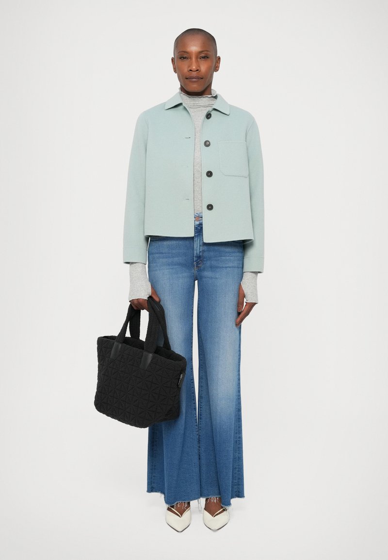Lyseblå cropped jakke, grå turtleneck, flagrende blå jeans, sort quiltet tote bag og hvide stiletter med sorte accenter.