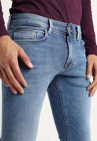 Vaaleansininen suorahkoistettu farkut, valmistettu denimiä. Ominaisuuksiin kuuluu viiden taskun muotoilu ja hienovaraiset kulumajäljet, sekä ommeltu vyötärönauha.