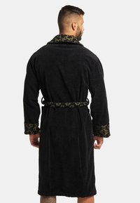 Black bathrobe made of terry cloth. Features a patterned green collar and cuffs. Includes a matching belt for closure.