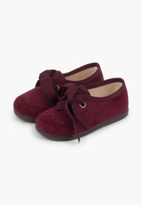 Scarpe in suede bordeaux con punta tonda, dotate di un fiocco in raso e perforazioni decorative, su una suola in gomma flessibile.
