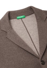 Brązowy dziany kardigan z kołnierzem szalowym, z zapięciem na guziki i miękką teksturą. Etykieta głosi "United Colors of Benetton."