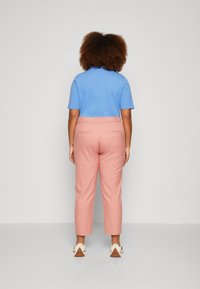 Lichtblauw shirt met korte mouwen en roze cropped broek van de achterkant weergegeven, met zijzakken en een gladde stofstructuur.