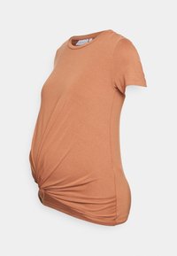 Maternity t-shirt in rust color, featuring a round neckline and short sleeves. The fabric is soft with a knotted detail at the front.