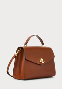 Brun läderhandväska med en strukturerad form, guldfärgade detaljer, ett handtag upptill och ett avtagbart axelband. Märkbar logodetalj på klaffen.