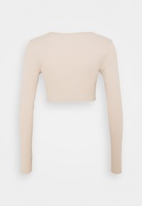 Haut court à manches longues beige avec un col rond et une texture côtelée douce. Design épuré sans motifs ni éléments matériels visibles.