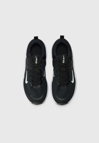 Black athletic shoes with a textured upper, lace closure, and white Nike swoosh logo. Features a cushioned sole and pull tab.