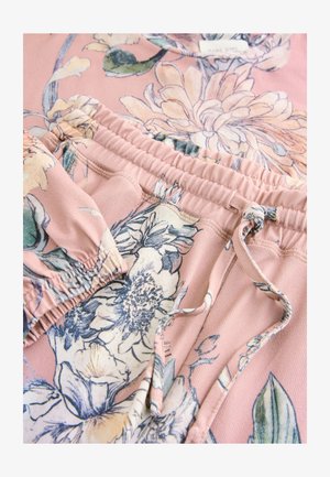 Lyserød blomstret top og matchende bukser med elastisk talje. Stoffet er blødt og prydet med store blomster i nuancer af blå og creme.