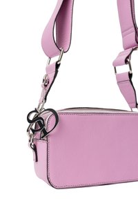 Borsa a tracolla in pelle rosa con una texture liscia, chiusura con zip e dettagli neri. Presenta un charm con logo in argento e una tracolla regolabile.