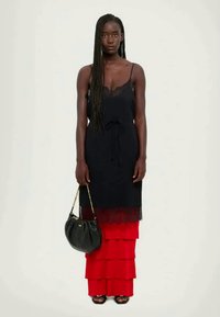 Must mustriga mustriga kleit mustriga mustriga punase kihilise seelikuga, millel on paelaga vöökoht, koos musta käekotiga ja mustade rihmadega sussidega.