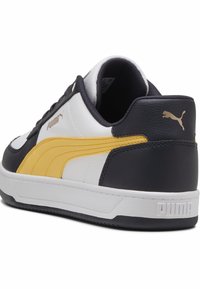 Puma sneakers i sort, hvid og gul. Har lædermateriale, lav-top design, polstret krave og logo-detaljer på hælen.
