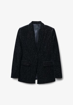 Blazer en velours noir avec une coupe slim, revers crantés, deux poches avant et une texture subtilement à pois. Le tissu paraît doux et luxueux.