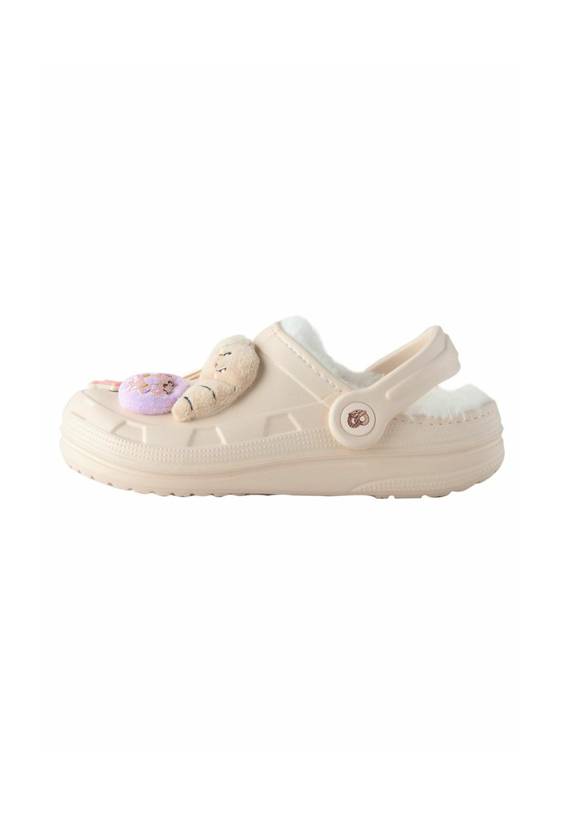 Chaussures slip-on beiges avec un intérieur pelucheux, ornées de décorations en peluche ludiques incluant un ours et un donut, conçues pour le confort.