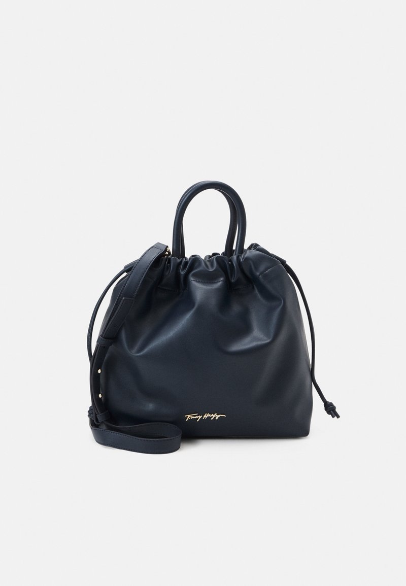 Sac à main en cuir noir avec cordon de serrage, double poignées, bandoulière amovible et logo doré discret au centre avant.