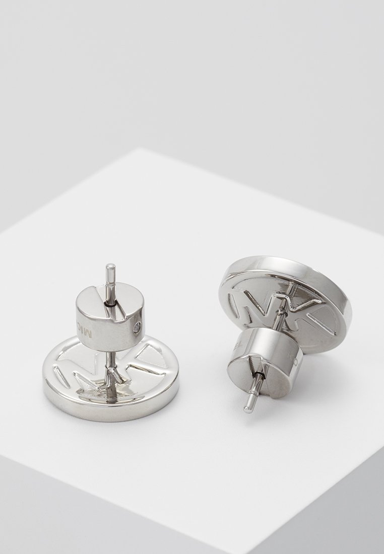 Orecchini in metallo con base circolare e dettagli del logo in rilievo. Finitura argentata lucida, dotati di chiusura a perno per una vestibilità sicura.
