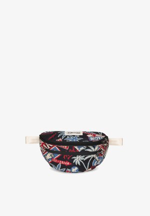 Riñonera de tela en negro con gráficos multicolores, que incluyen palmeras y varios parches con temática de viajes. Cuenta con un cierre con cremallera y una correa.