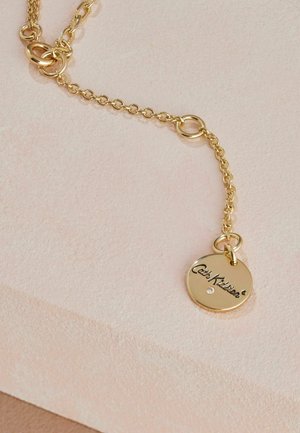Goldkette mit Gliedern, featuring a runden Anhänger mit graviertem Text und einem kleinen Edelsteinakzent. Glatte, glänzende Oberfläche.