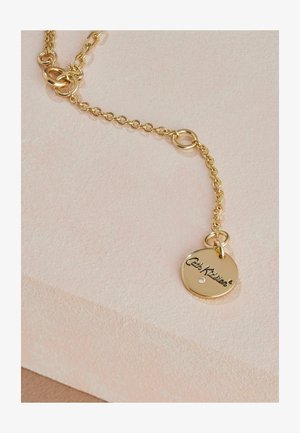 Collier en or avec maillons, présentant un pendentif rond avec un texte gravé et un petit accent en pierre précieuse. Surface lisse et brillante.