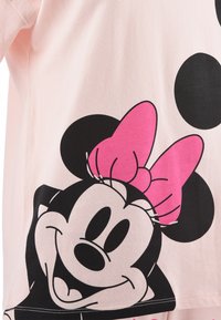 Camiseta de color rosa claro con un gran gráfico en negro y rosa de un personaje de dibujos animados con orejas grandes y un lazo decorativo.