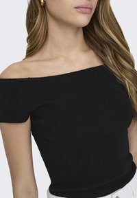 Melnā off-the-shoulder ribbed blūze ar pieguļošu dizainu un īsām piedurknēm. Gluda tekstūra un minimāli šuvju detaļas.