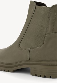 Bottines vert olive en cuir lisse avec des panneaux latéraux élastiques, bout rond, tige texturée et semelle en caoutchouc.