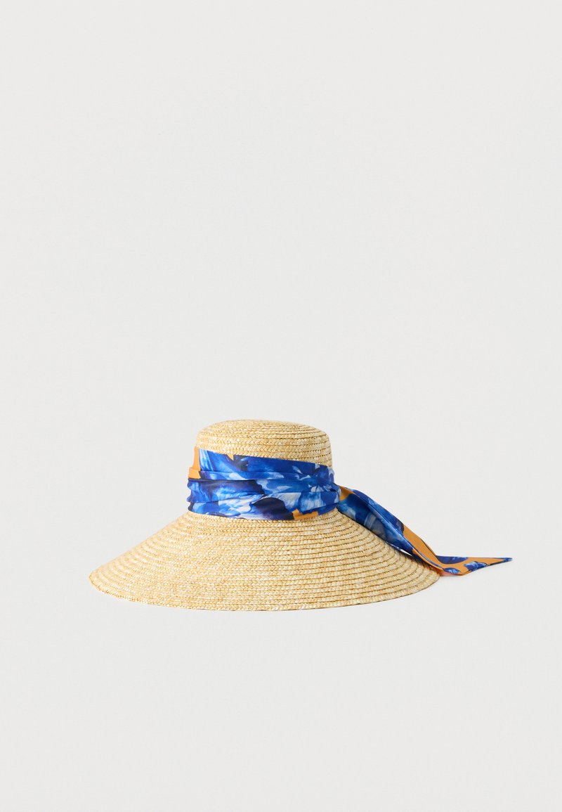 Chapeau de soleil en paille à large bord avec un foulard floral bleu et orange noué autour de la calotte, présenté sur un fond uni.