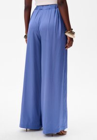 Pantalons évasés bleu clair en tissu doux, avec une taille élastique et une texture lisse, finement ourlés à la cheville.