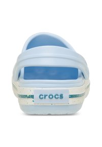 Himmelblaue Crocs mit einem breiten Riemen und einer offenen Rückseite; ausgestattet mit einer gesprenkelten weißen Sohle mit blauen Akzenten und einem Logo an der Ferse.