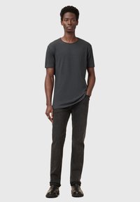 Grå kortærmet t-shirt lavet af bomuld, parret med mørke jeans og sorte sko, præsenterer en afslappet og uformel silhuet.