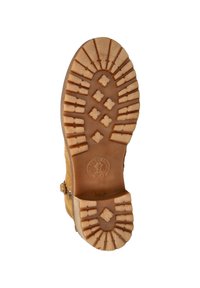 Tan suede boot sole with a textured grip pattern, featuring grooves and diamond shapes for traction. Logo embossed near the heel.