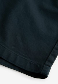 Dunkelblauer Stoff mit glatter Textur, gefaltetem Rand und sichtbaren Nähdetails. Geeignet für legere oder formelle Bekleidungsanwendungen.