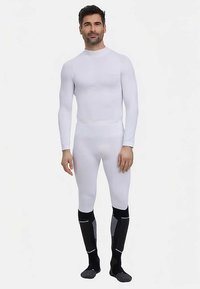 Witte thermische baselayer met lange mouwen, nauwsluitend ontwerp, rekbare stof, gecombineerd met zwart-grijze kniehoge sokken met accenten.