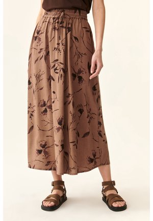 Bruine bloemen midi-rok met aantrekkoord in de taille, gedragen met bruine platte sandaaltjes met bandjes op een lichte achtergrond.